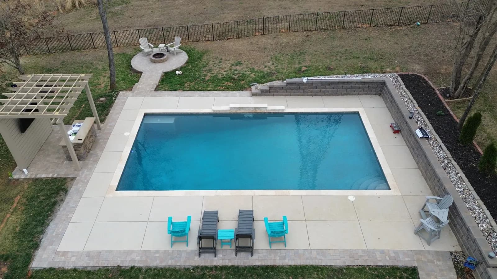 Aerial view of a finished pool, paver deck, and retaining wall by Precision Hardscapes