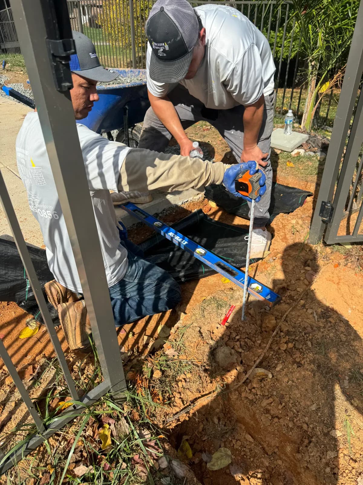 Precision Hardscapes crew measuring and setting grade on site