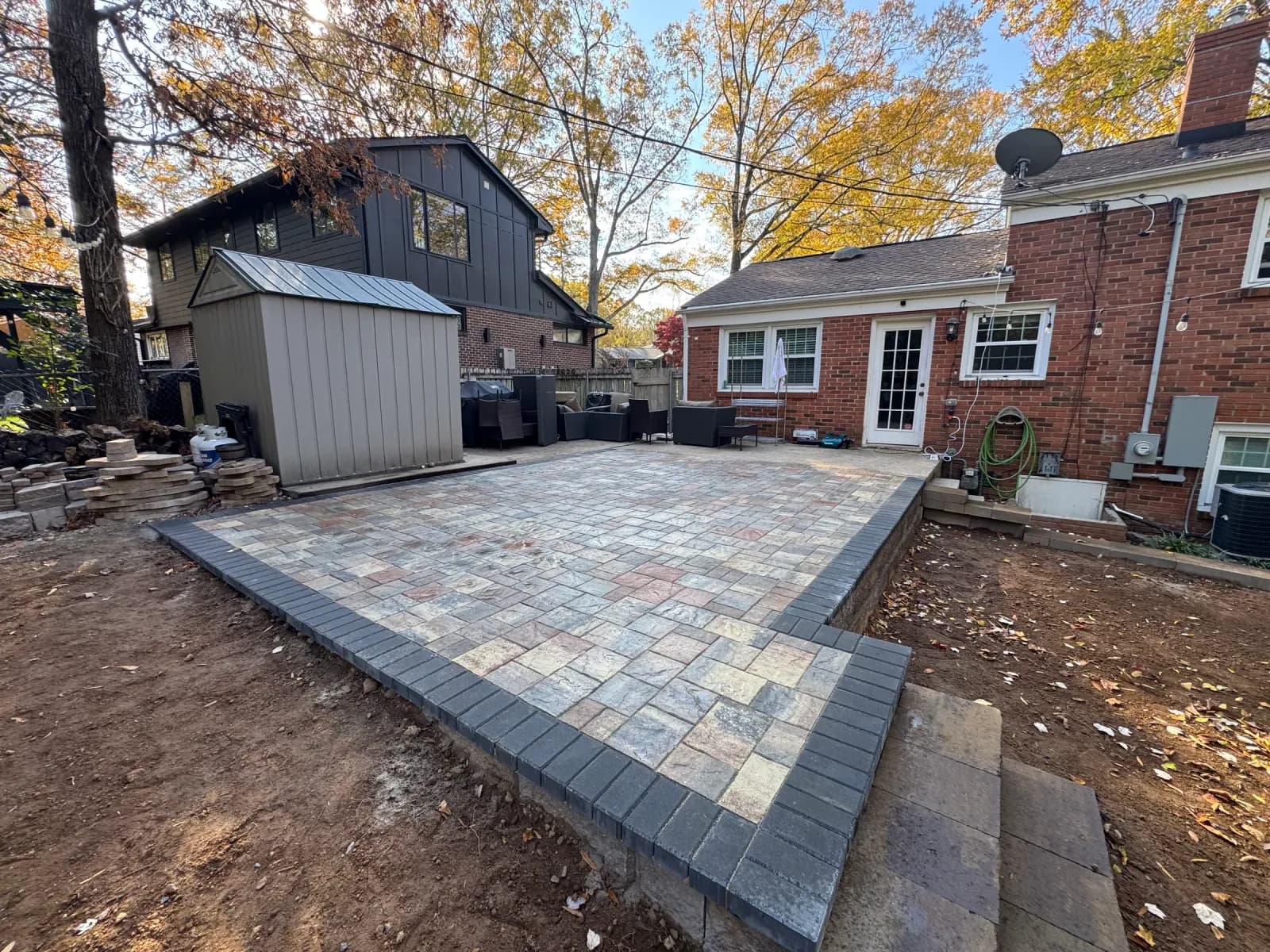 Finished paver patio and steps beside a brick Charlotte home